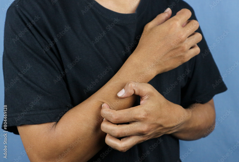 Asian young man scratching his hand isolated on blue background. Asian young man scratching his hand isolated on blue background.