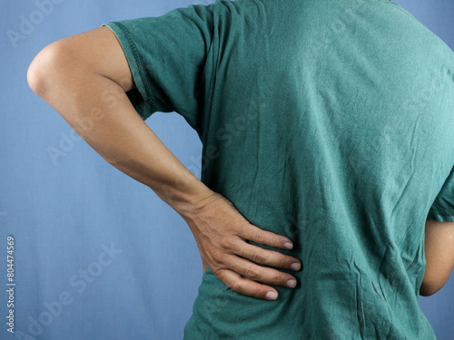 Close-up rear view of man's hand touching back pain, low back pain concept. photo