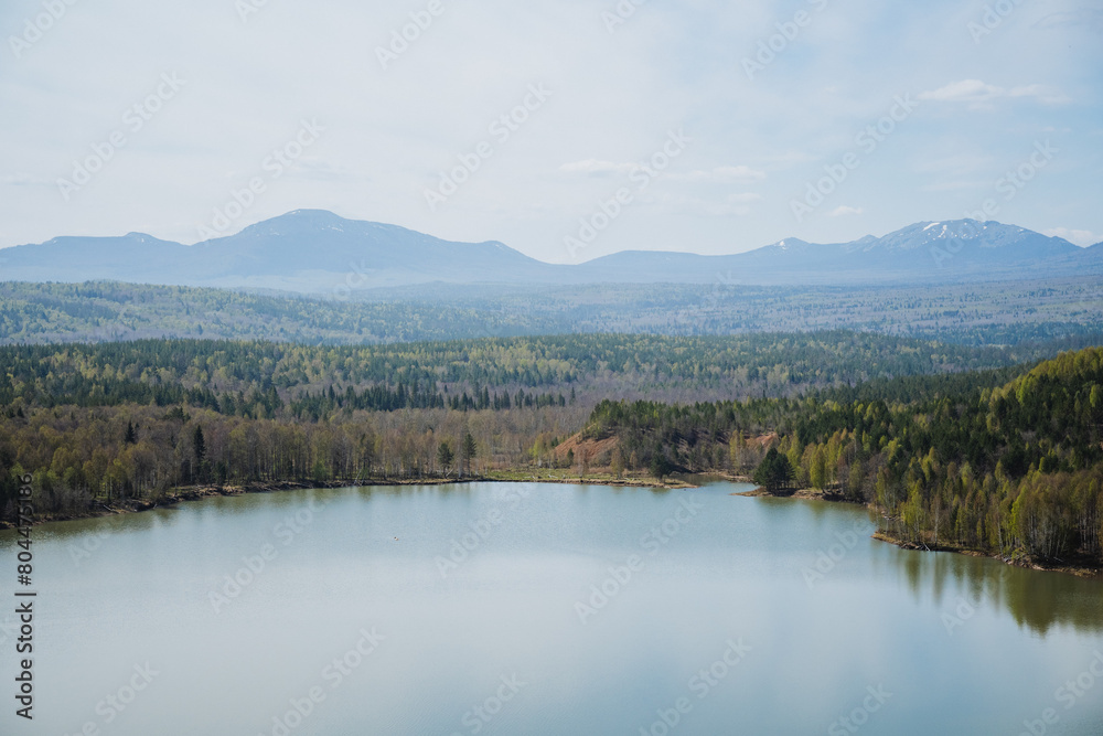 Obraz premium A lake lies in a forest with mountains framing the skyline