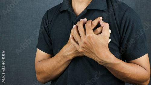 Man clutching his chest from acute pain. Heart attack symptom pressing on chest having painful cramp photo