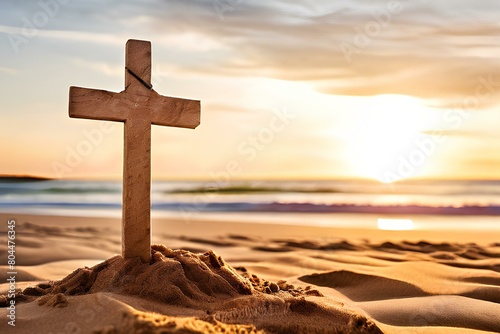 Small wooden Christian cross in sand on the beach with sea in background and copy space.
