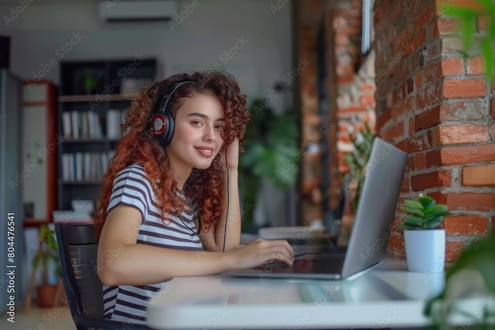 A young Brazilian female student sitting at the table using headphones when studying A young Brazilian female student sitting at the table using headphones when studying