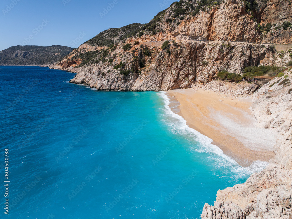 A serene view of Kaputaş Beach in Kalkan, Turkey, with turquoise waters, golden sand, and a peaceful atmosphere, perfect for relaxation.