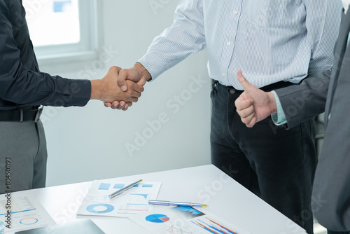 Two businessmen are shaking hands in office while sitting at the desk, Business people concept