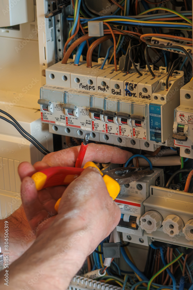 An electrician works on a fuse box