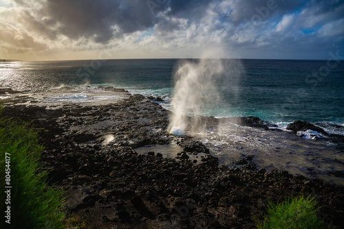 2023-13-31 THE BEAUTIFUL SPOUTING HORN SPRATING WATER INTHE AIR WITH A BEAUTIFUL SKY AND SUNSET WITH A REFLECTION OFF OFTHE ROCKS ON KAUAI HAWAII
