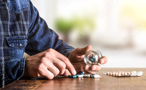 Person taking a pill on a wooden table