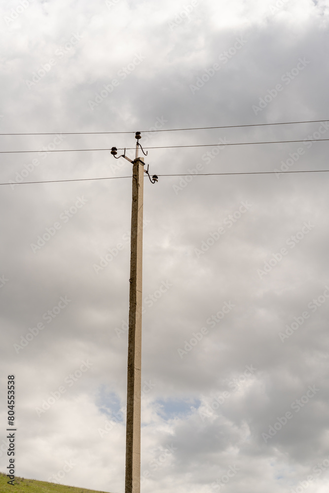 A tall pole with power lines on it. The sky is cloudy and the sun is not visible A tall pole with power lines on it. The sky is cloudy and the sun is not visible