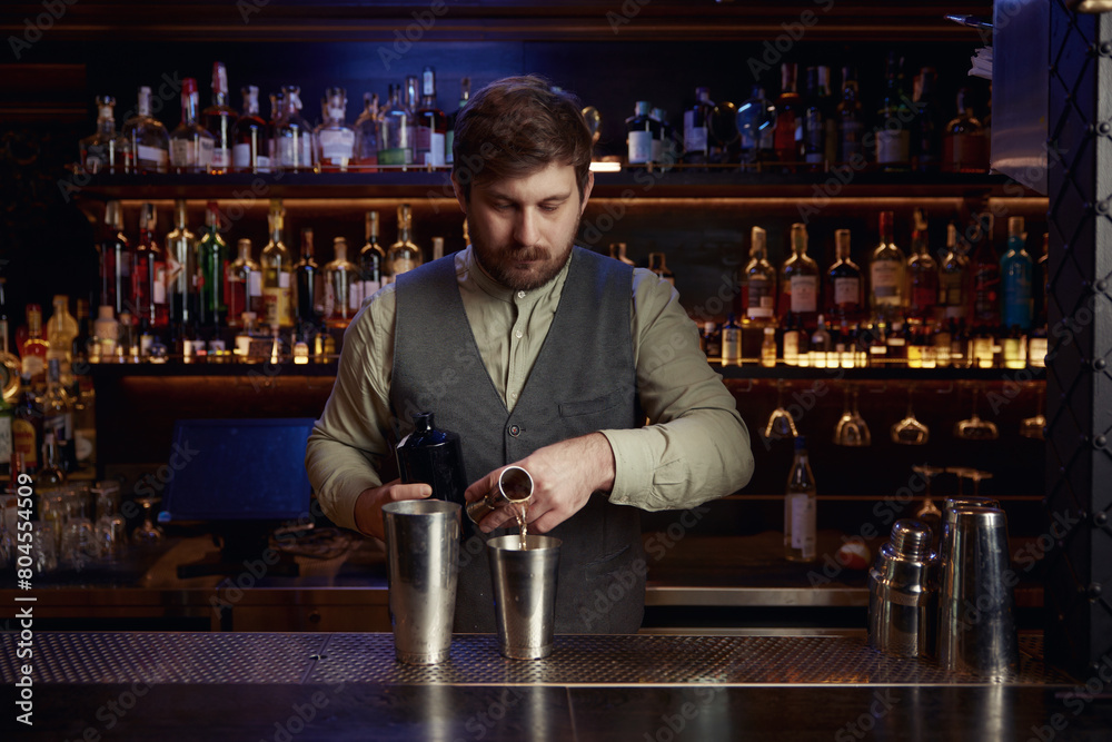 Confident bartender male pouting liquor to make cocktail