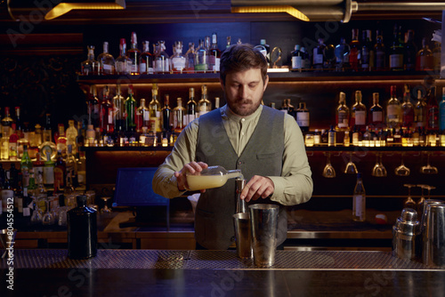 Photography Confident bartender male pouting liquor to make cocktail