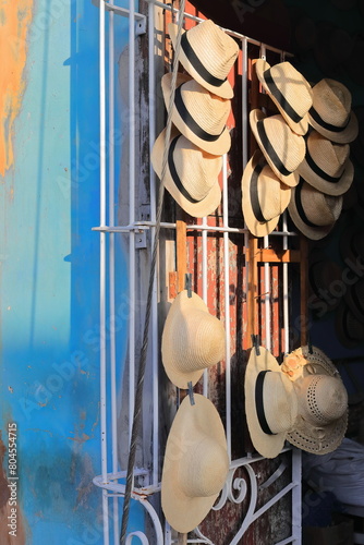 Straw hats -Panama, Ecuadorian- for sale hanging from the white-grille of the door of a shop in the Plaza Mayor Square area. Trinidad-Cuba-231
