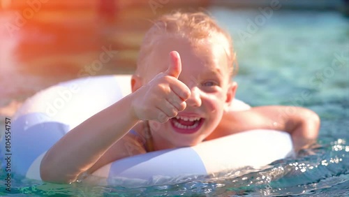 Funny cute baby girl on summer vacation. Kid with swim ring in swimming pool. Summer family vacations concept. 