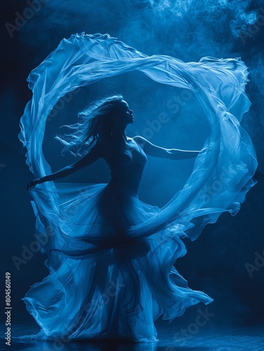 A woman dances with a blue cloth flowing around her body. photo