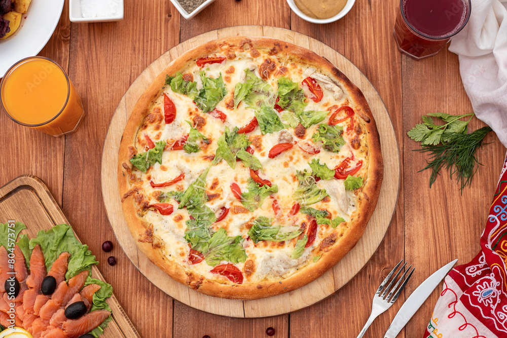 Caesar pizza on a set table, against the background of a wooden board, with cutlery, serving option Caesar pizza on a set table, against the background of a wooden board, with cutlery, serving option