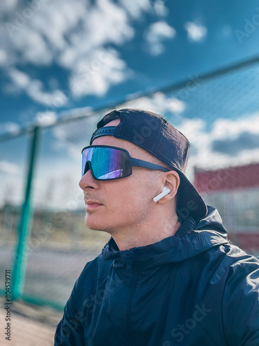 male runner in sportswear, glasses and headphones outdoors. Selfie portrait on a smartphone