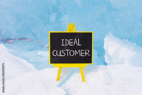 Ideal customer symbol. Concept words Ideal customer on beautiful yellow black blackboard. Beautiful blue ice background. Business ideal customer concept. Copy space.