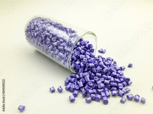Violet pearl masterbatch granules in a glass tube on a white background, this polymer is a colorant for products in the plastics industry