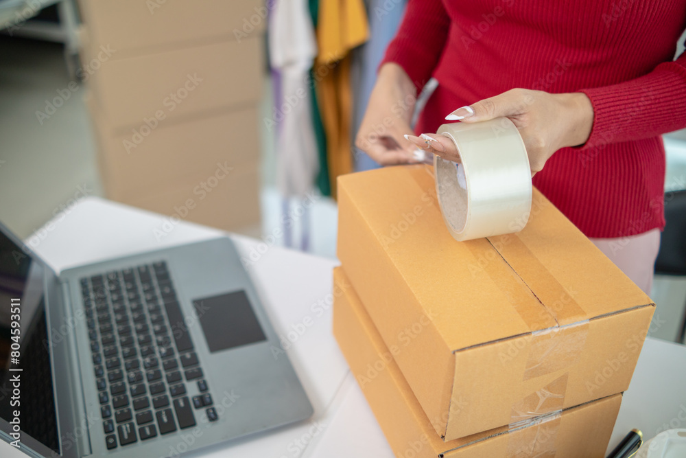 SME business operator is inspecting and packing products into parcel box for delivery company that will come pick up products after participating in online marketing with Application shopping online SME business operator is inspecting and packing products into parcel box for delivery company that will come pick up products after participating in online marketing with Application shopping online