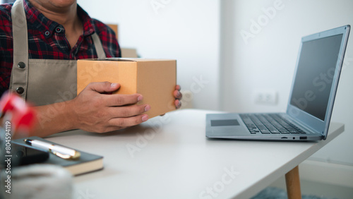 SME business operator is inspecting and packing products into parcel box for delivery company that will come pick up products after participating in online marketing with Application shopping online