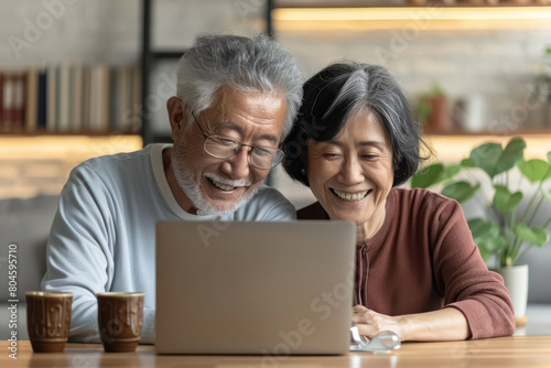 With smiles on their faces, a mature couple enjoys a loving online interaction, participating in a video call together on their laptop, symbolizing the warmth and connection that technology brings to