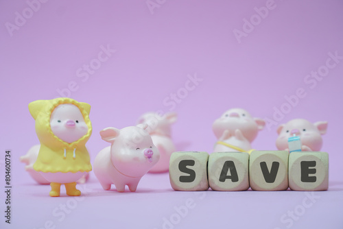 A group of toy pigs with one wearing a yellow raincoat standing in front of the word SAVE.