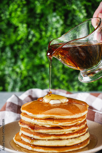 fresh tasty pancakes with maple syrup on a light stone background