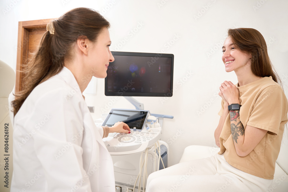 Gynecologist and happy woman looking at each other after ultrasound scanning Gynecologist and happy woman looking at each other after ultrasound scanning