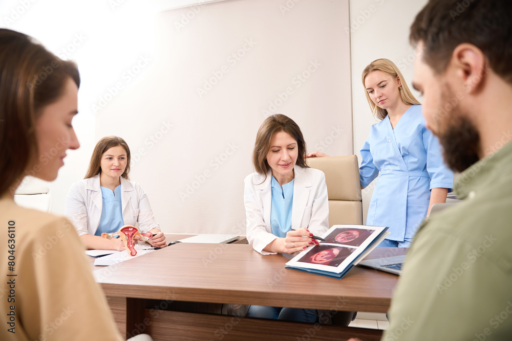 Gynecologist showing to doctors and pregnant couple results of ultrasound scan Gynecologist showing to doctors and pregnant couple results of ultrasound scan