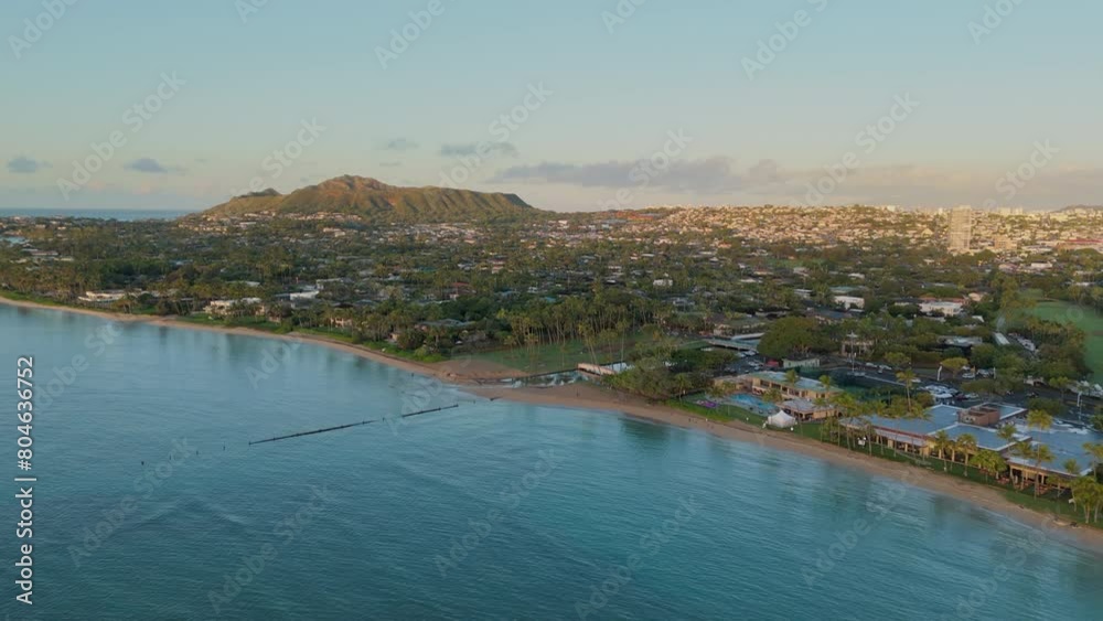 An aerial perspective highlights a residential area nestled between lush tropical greenery and a sandy beach as the sun sets over Honolulu, creating a serene atmosphere. Hawaii island, Oahu, Honolulu An aerial perspective highlights a residential area nestled between lush tropical greenery and a sandy beach as the sun sets over Honolulu, creating a serene atmosphere. Hawaii island, Oahu, Honolulu