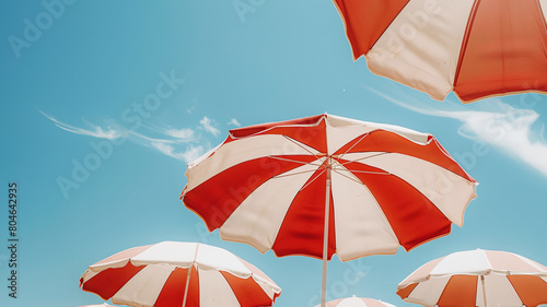 Vibrant beach umbrellas stand against a clear blue sky, symbolizing leisure and summer vibes.