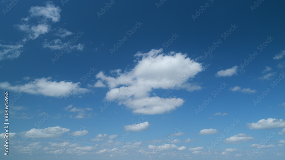 Blue sky with stratocumulus clouds and sun. Stretching and flowing white cumulus clouds in blue sky. Timelapse.