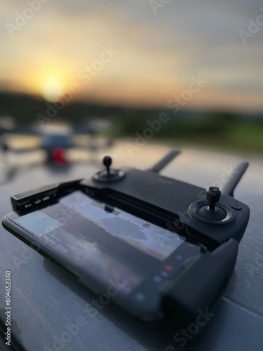 Kontroler drona z wyświetlaczem i dron w tle w plenerze ze wschodem słońca photo