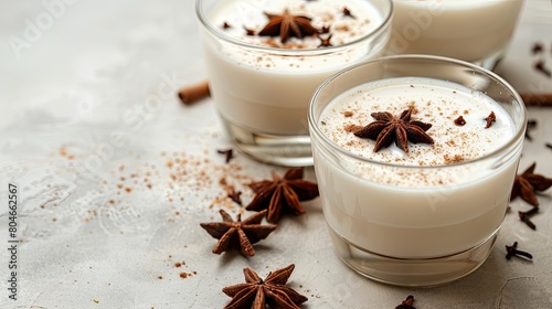 glasses of white coconut milk infused with cinnamon, set against a dark grey background, offering a visually appealing contrast and leaving ample space for text. © lililia