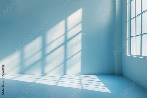 A minimalist room featuring a blue wall and a window  with shadows and sunlight entering the space