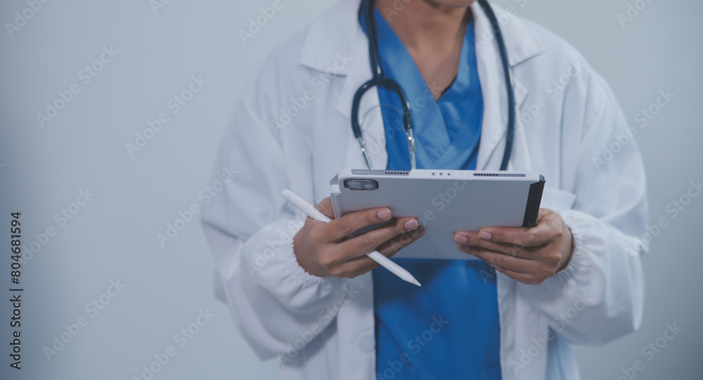 Woman doctor using tablet computer while standing straight in hospital Woman doctor using tablet computer while standing straight in hospital