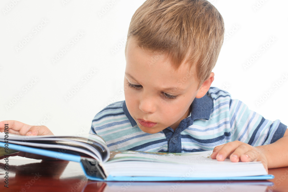 studio portrait of a confused little boy reeding a book