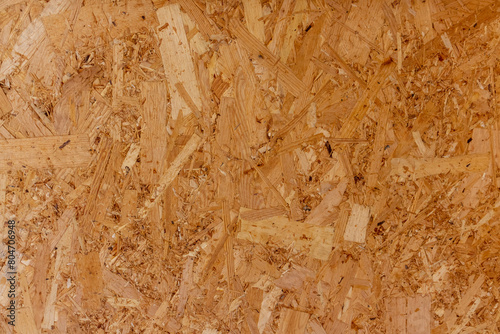 Abstract brown wooden particle board (particleboard, chipboard, or low-density fiberboard) background. Close-up view of recycled compressed wood chippings board surface. Construction material theme. photo
