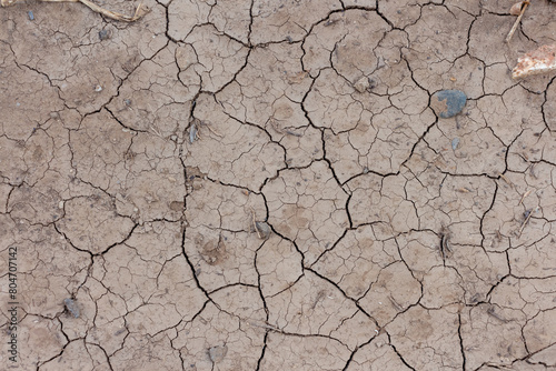 Close-up top view of dry brown cracked cly land surface in a summer day. Abstract weather background. Soft focus. Copy space. Drought and climate change theme.
