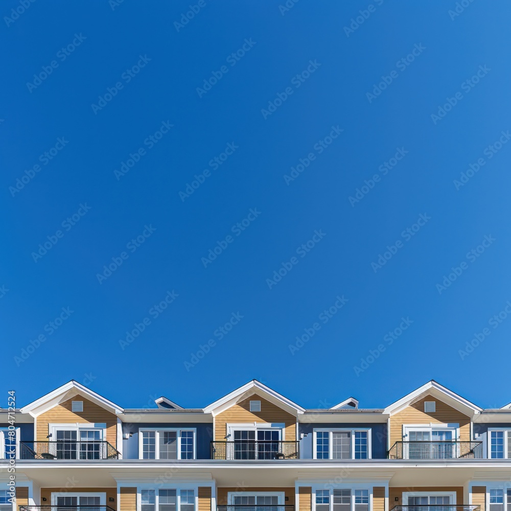 A graphic depiction of a row of bright yellow residential buildings against a clear blue sky captured from a low angle A graphic depiction of a row of bright yellow residential buildings against a clear blue sky captured from a low angle