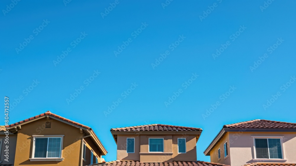 Neutral-colored suburban houses line up against a vibrant blue sky, showcasing the calmness of residential life Neutral-colored suburban houses line up against a vibrant blue sky, showcasing the calmness of residential life