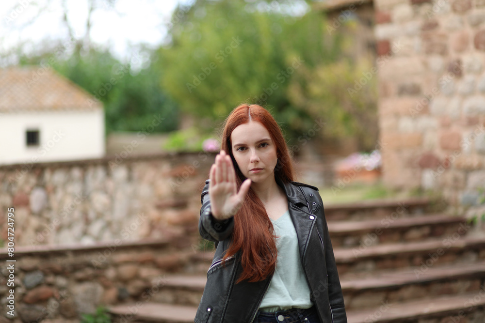 Woman with serious face makes the stop gesture with her hand raising her arm Woman with serious face makes the stop gesture with her hand raising her arm
