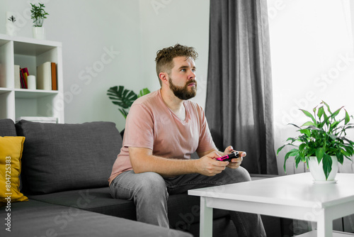 Man playing videogames in living room sitting on sofa.