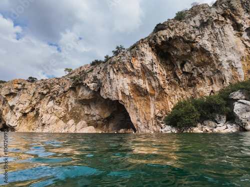 View from the water of Lake Vouliagmeni to a rock and sky with clouds, photo with an action camera.