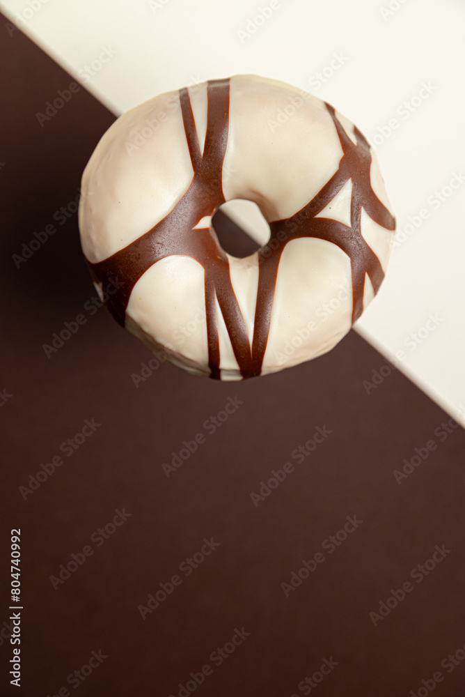 A chocolate and white donut with a brown stripe. The donut is sitting on a black and white background