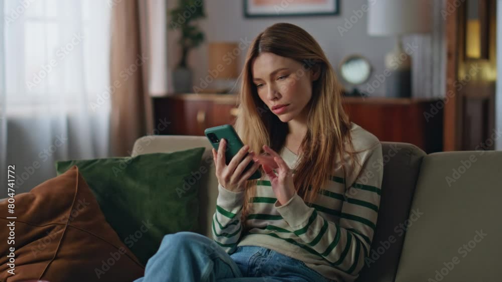 Stressed girl looking cellphone screen reading bad news at couch. Upset woman