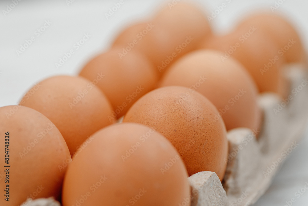 orange hen eggs lying in cardboard box, dozen eggs on white wooden background, selective focus orange hen eggs lying in cardboard box, dozen eggs on white wooden background, selective focus