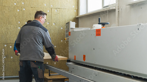 worker standing at modern computer machine and working with wooden planks at factory. High quality photo