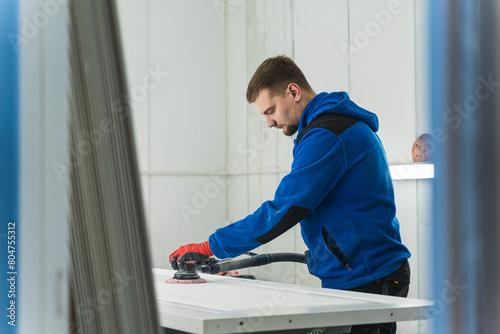 Male carpenter using orbital electric sander in a workshop. High quality photo