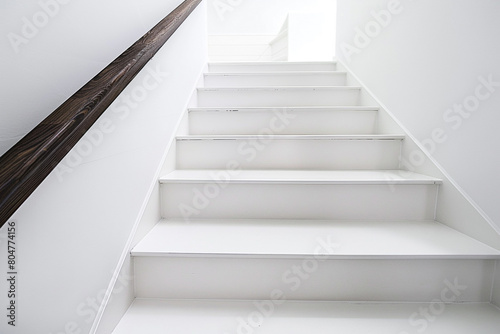 Pure white stairs with a contrasting dark wooden handrail, minimalistic and clean. © Naeem