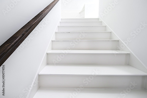 Pure white stairs with a contrasting dark wooden handrail, minimalistic and clean.